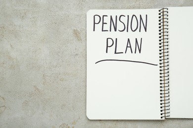 Photo of Notebook with words Pension Plan on light textured table, top view. Space for text