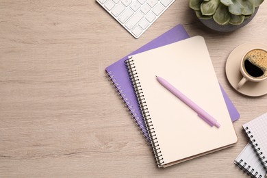 Photo of Flat lay composition with spiral notebooks, coffee and pen on wooden table. Space for text