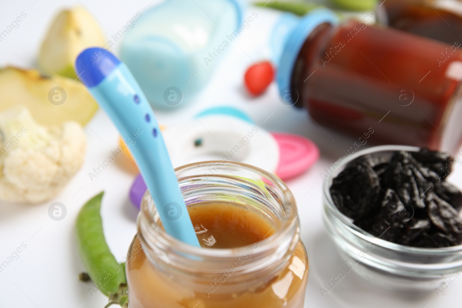 Photo of Jar with healthy baby food and spoon on table, closeup