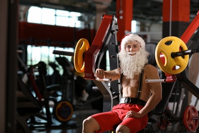 Photo of Young muscular man in Santa costume training at gym