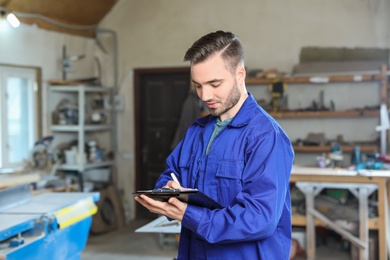 Young working man in uniform taking order at carpentry shop