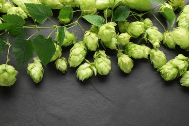 Fresh green hops and leaves on black table, above view. Space for text