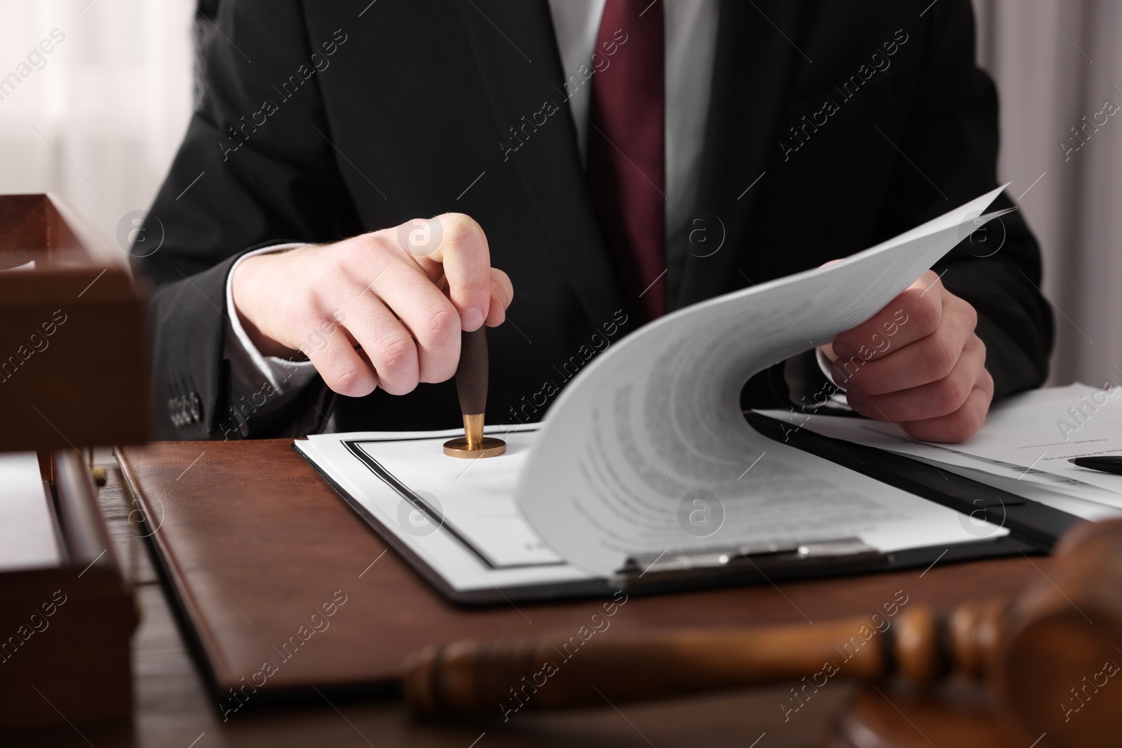 Photo of Notary stamping document at table in office, closeup