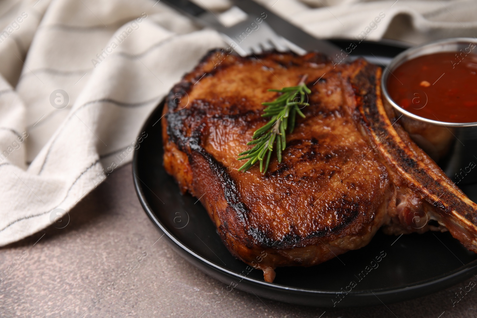 Photo of Tasty grilled meat, rosemary and marinade on brown textured table, closeup