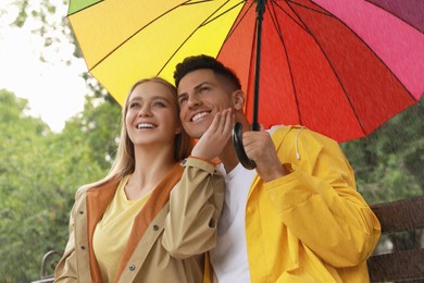 Lovely couple with umbrella under rain in park