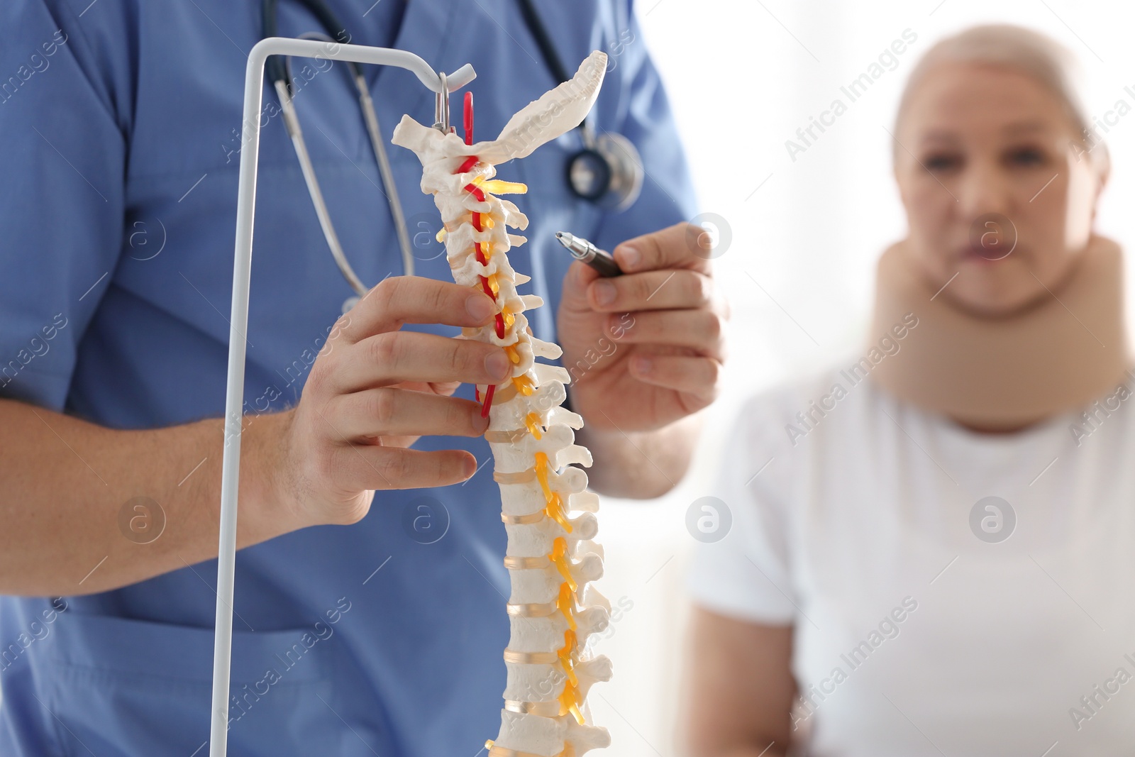 Photo of Male orthopedist explaining structure of spine to patient, closeup