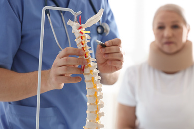 Male orthopedist explaining structure of spine to patient, closeup