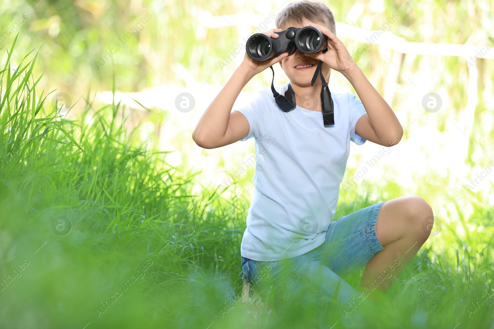 Photo of Little boy with binoculars outdoors. Summer camp