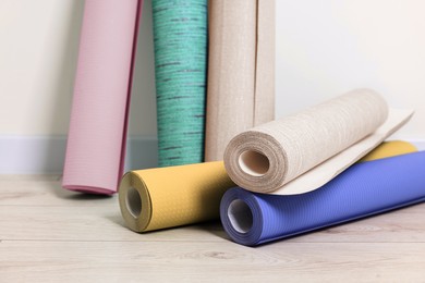 Image of Colorful wallpaper rolls on light wooden floor in room