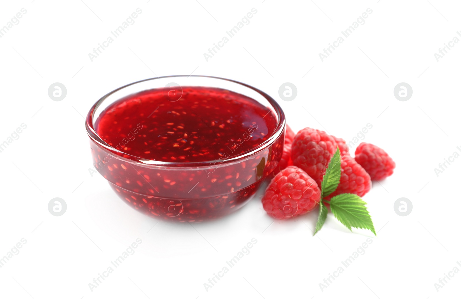 Photo of Bowl of sweet jam with ripe raspberries and green leaves on white background