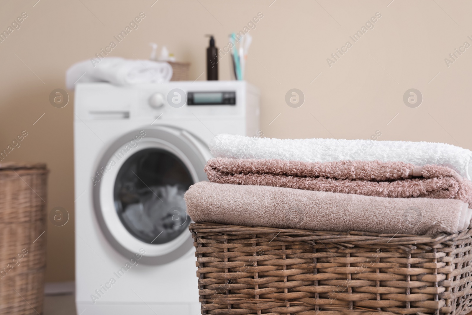 Photo of Basket with laundry and washing machine on background. Space for text