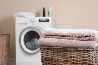Photo of Basket with laundry and washing machine on background. Space for text