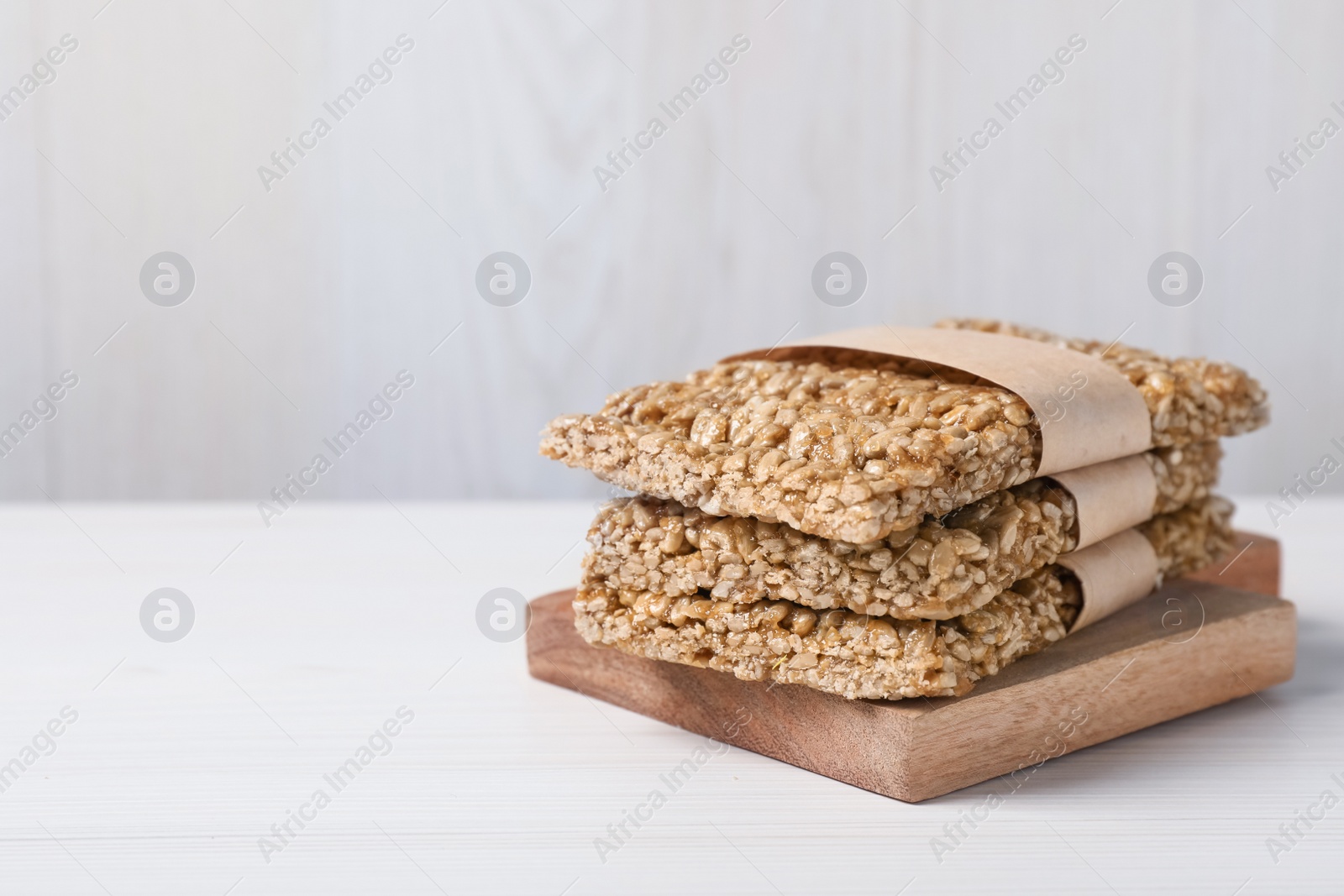 Photo of Delicious sweet kozinaki bars on white wooden table. Space for text