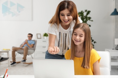 Photo of Happy mother and her teenager daughter with  laptop at home