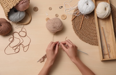 Photo of Woman knitting with threads at wooden table, top view. Engaging hobby