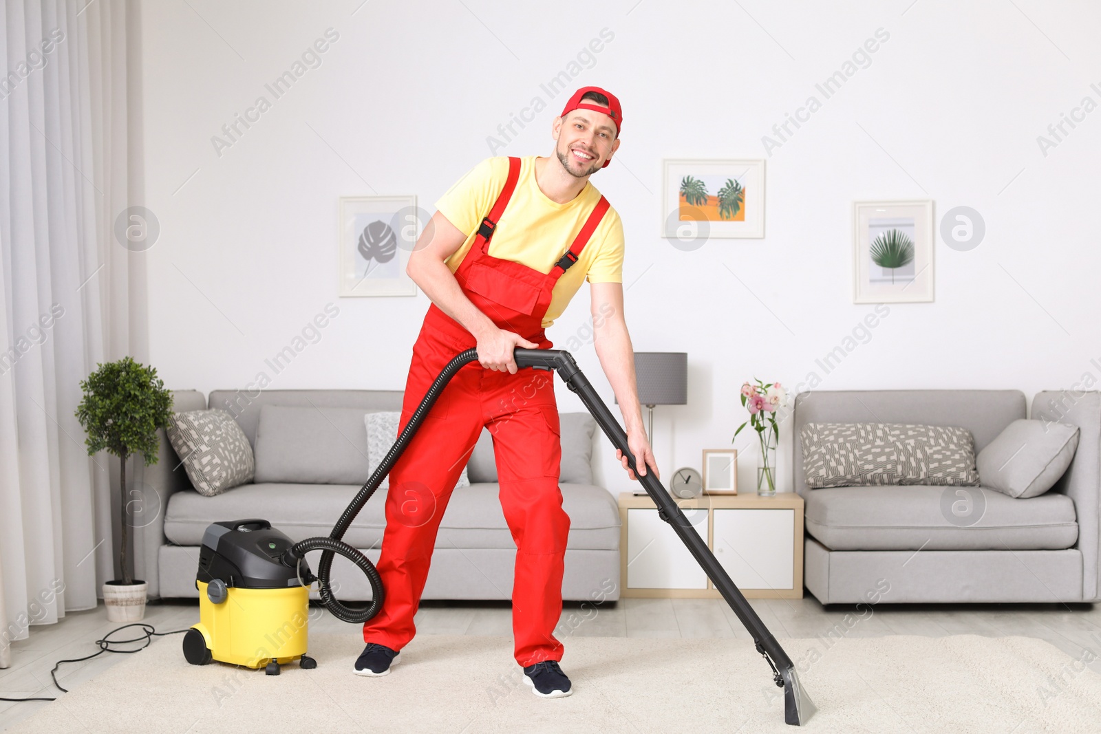 Photo of Mature man hoovering carpet with vacuum cleaner in living room