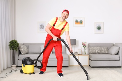 Photo of Mature man hoovering carpet with vacuum cleaner in living room