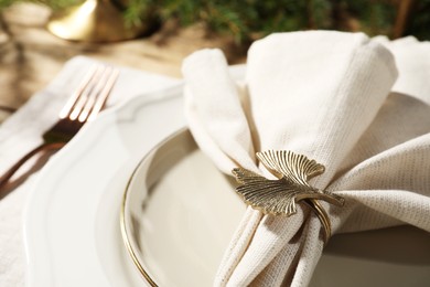 Photo of White fabric napkin with beautiful decorative ring for table setting on plate, closeup