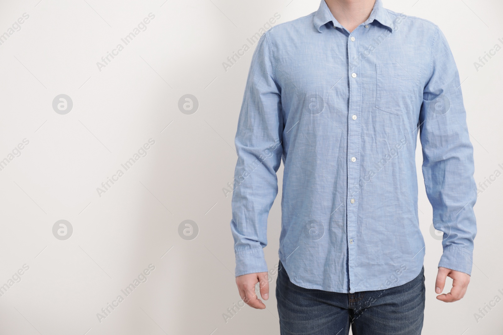 Photo of Man wearing rumpled light blue shirt on white background, closeup