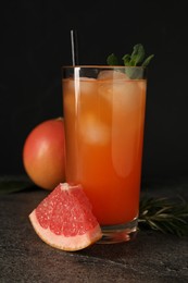 Tasty grapefruit drink with ice and mint in glass on dark textured table