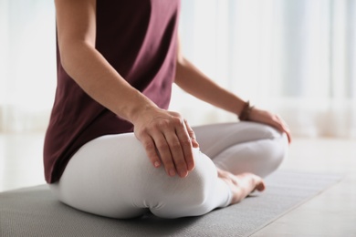 Woman practicing yoga on floor indoors, closeup. Space for text