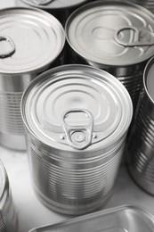 Photo of Many closed tin cans on white marble table, closeup