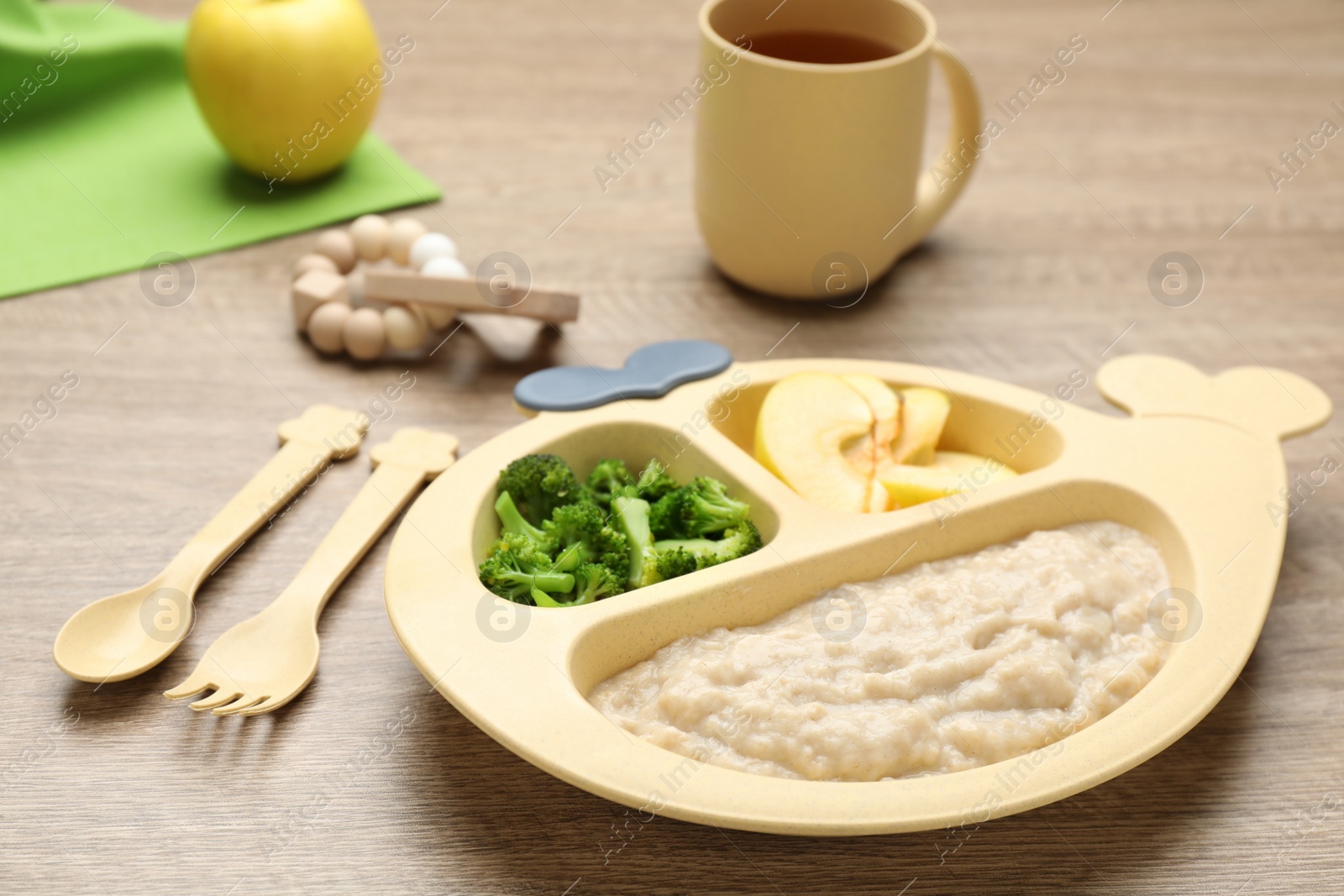 Photo of Plastic dishware with healthy baby food on wooden table