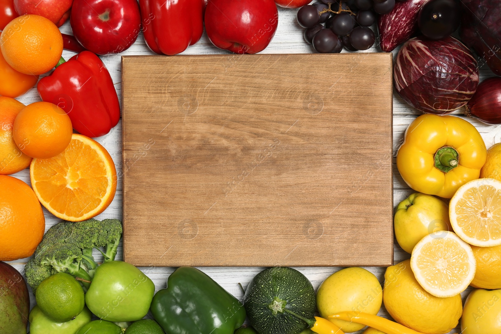 Photo of Wooden board in rainbow frame of fruits and vegetables, top view