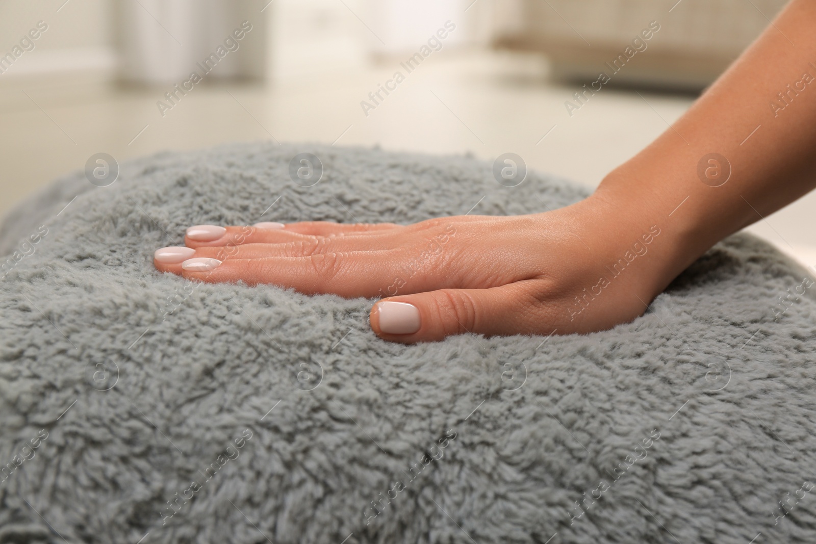 Photo of Woman touching soft grey cushion in room, closeup