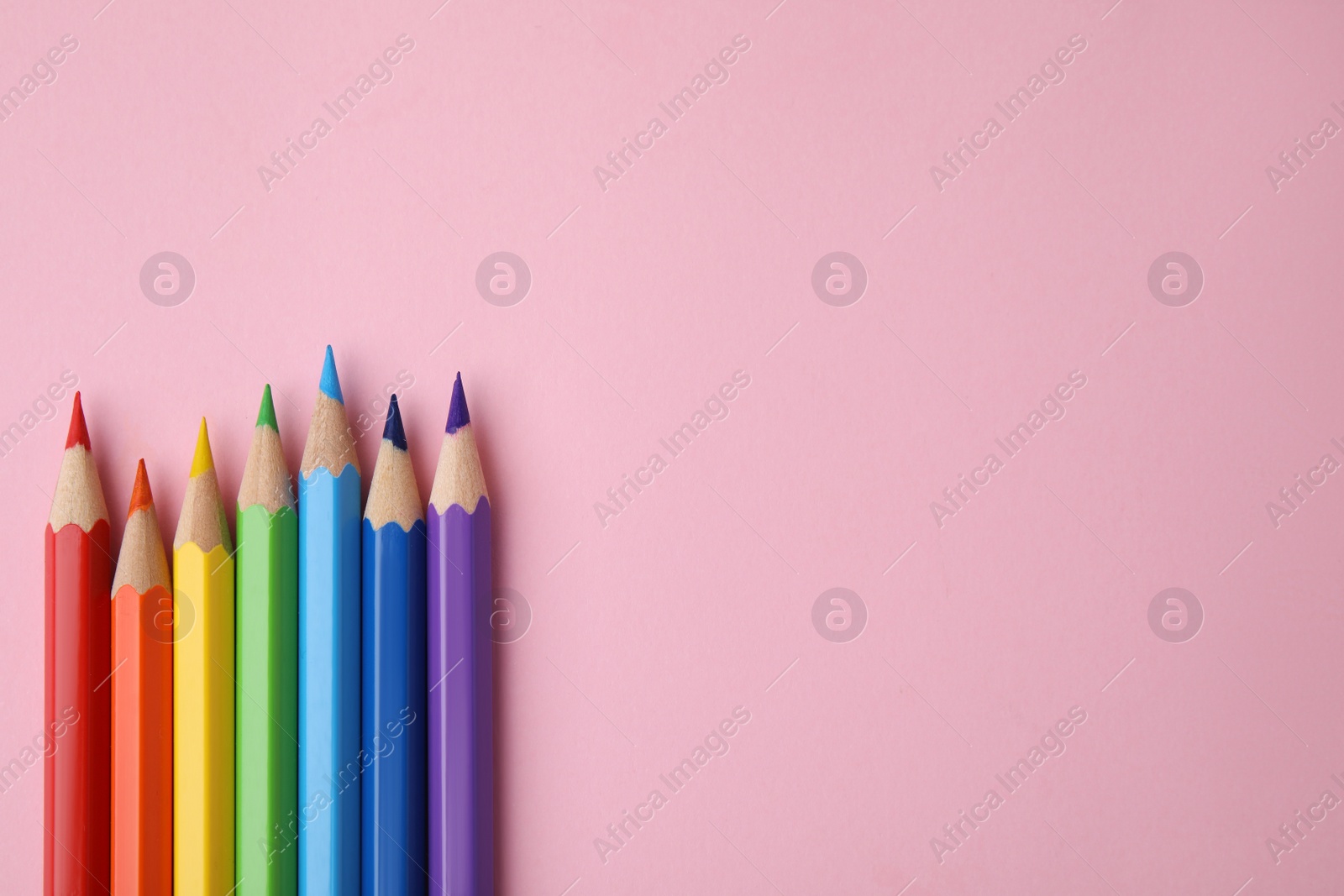 Photo of Colorful wooden pencils on pink background, flat lay. Space for text