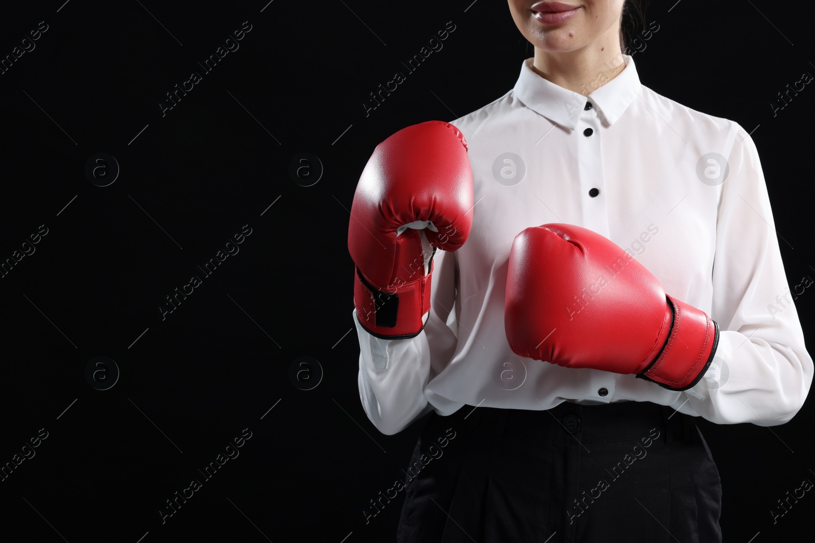 Photo of Businesswoman in shirt wearing boxing gloves on black background, closeup. Space for text