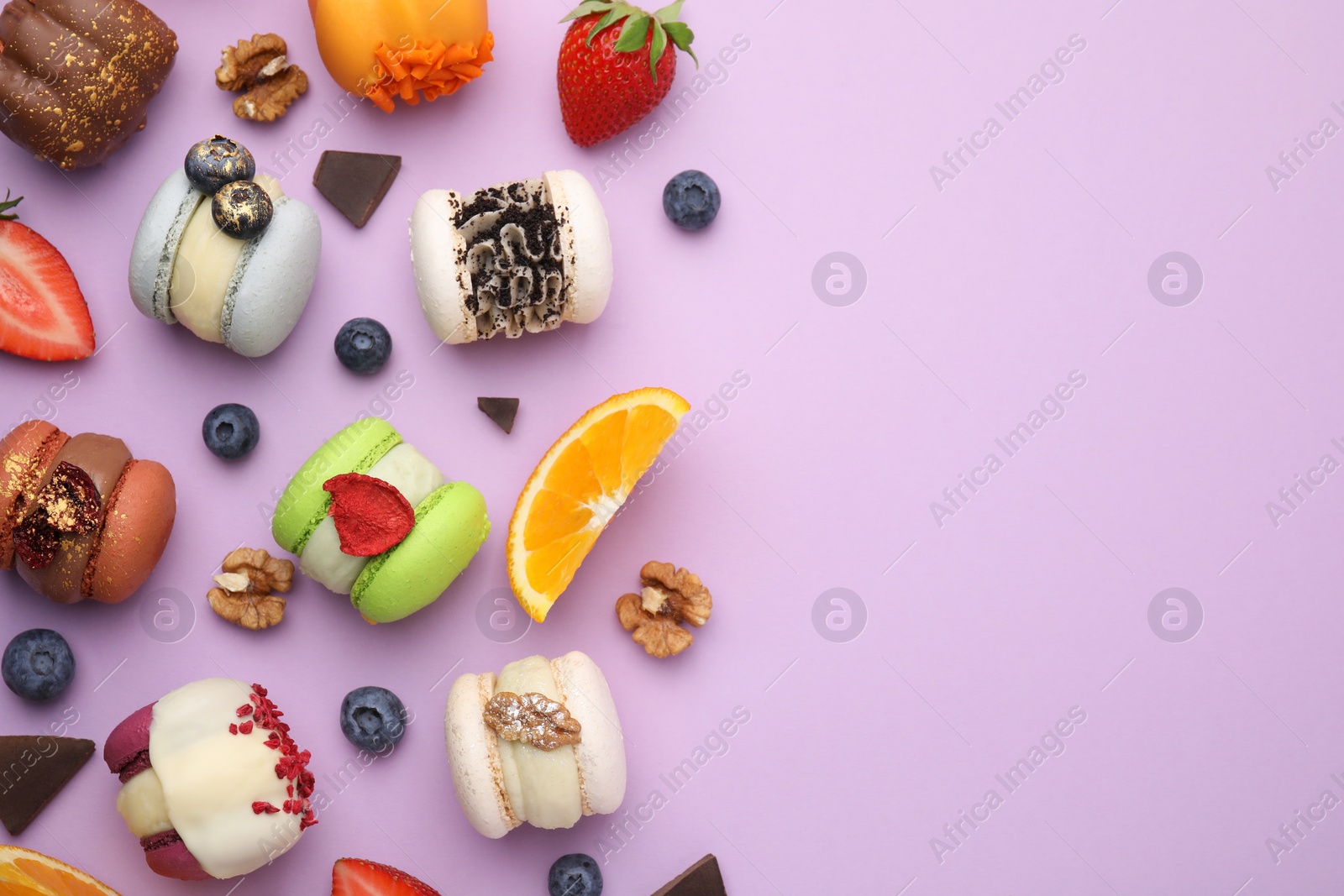 Photo of Delicious macarons, oranges and berries on violet table, flat lay. Space for text