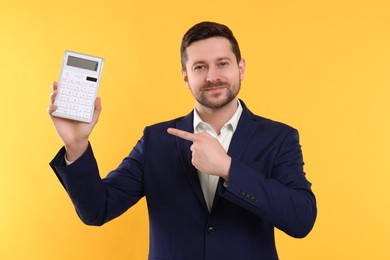 Photo of Happy accountant showing calculator on yellow background