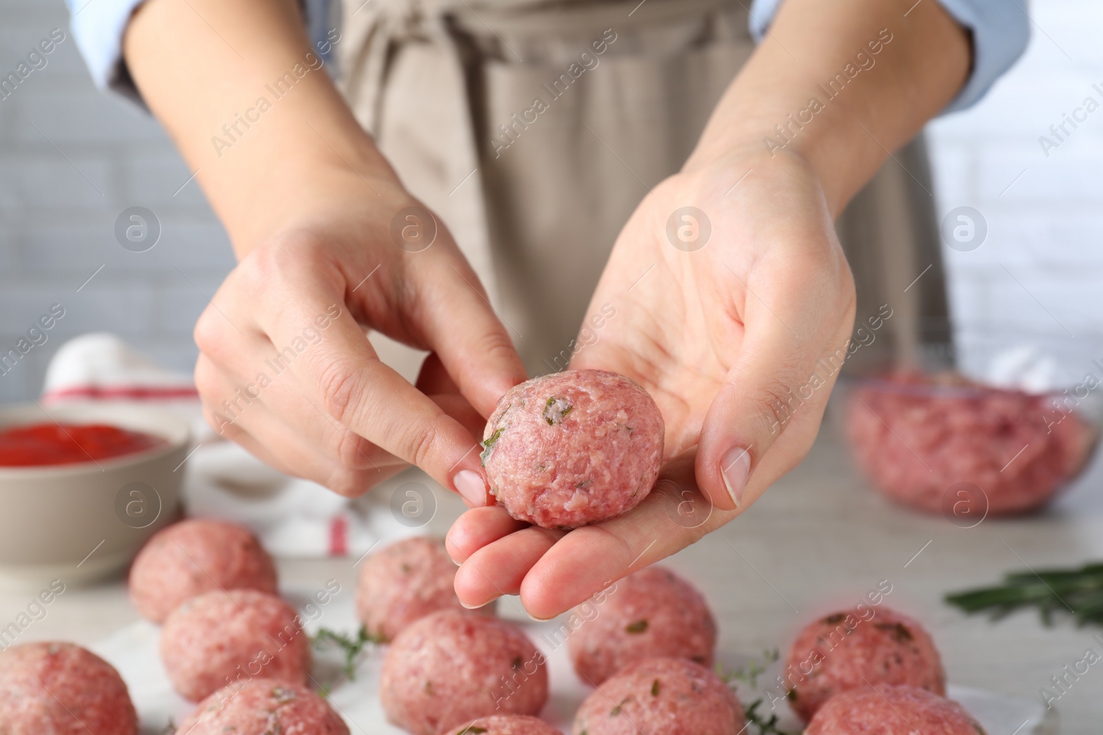 Photo of Woman making fresh raw meatballs at white table indoors, closeup