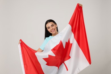 Photo of Happy young woman with flag of Canada on beige background