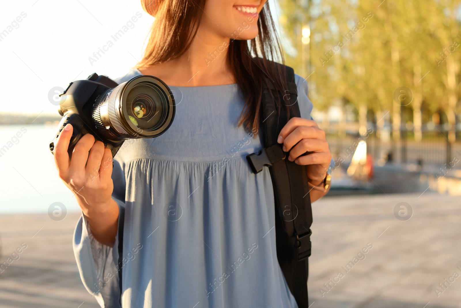Photo of Young female photographer holding professional camera at pier