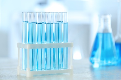 Photo of Test tubes with light blue liquid on table in laboratory