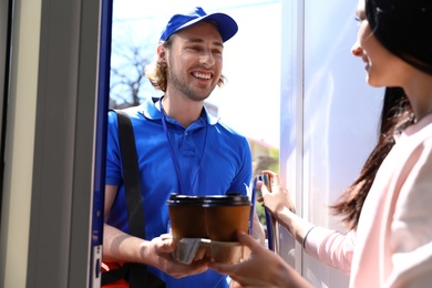 Photo of Woman receiving order from courier at door. Food delivery service