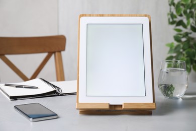 Photo of Modern tablet with blank screen and smartphone on table indoors. Space for text