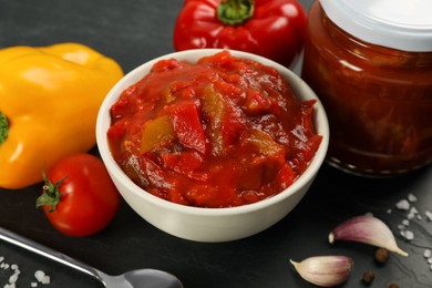 Photo of Delicious lecho and fresh ingredients on black table, closeup