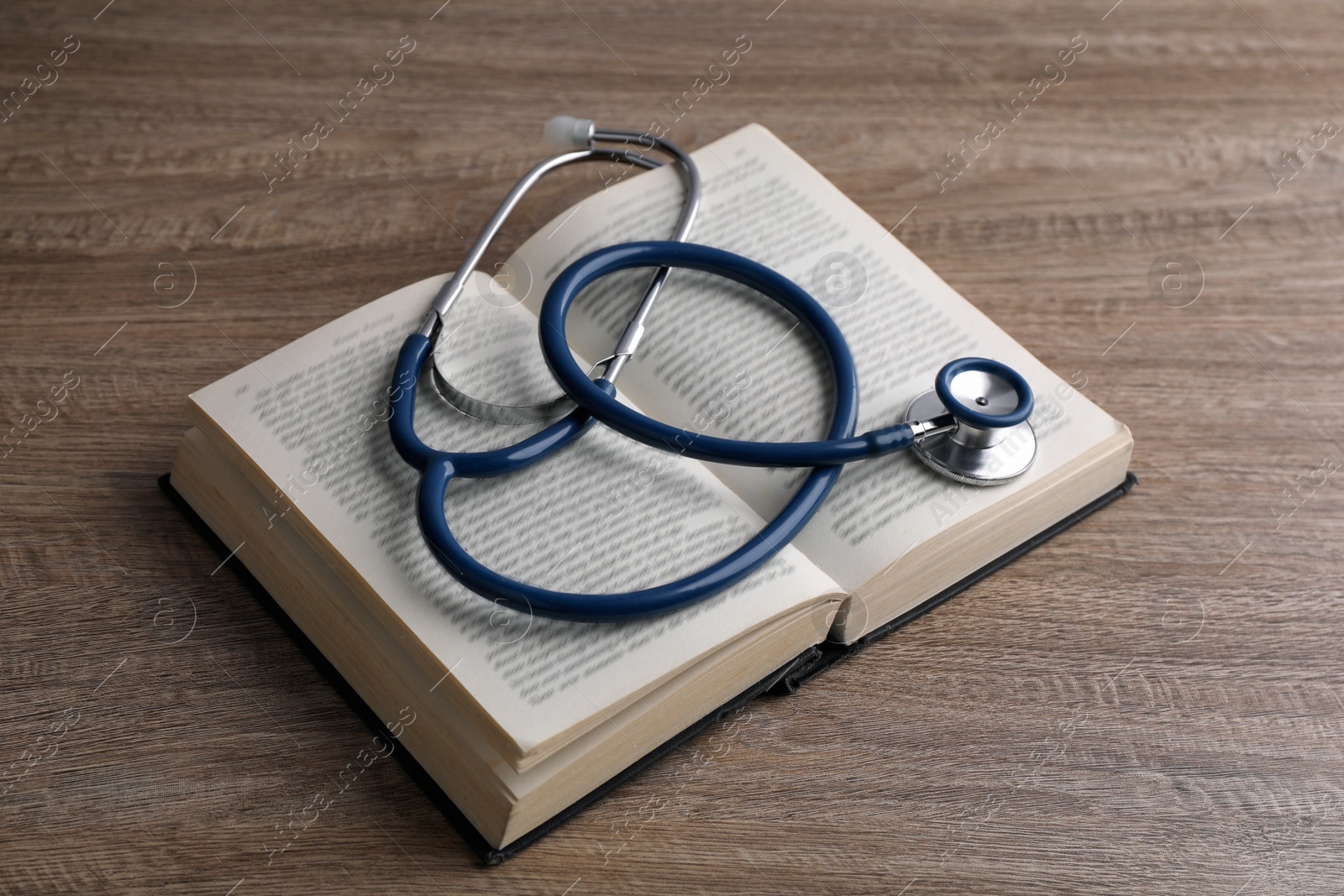 Photo of Student textbook and stethoscope on wooden table. Medical education