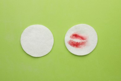 Clean and dirty cotton pads after removing makeup on green background, flat lay