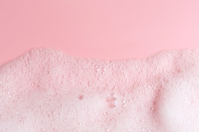 Photo of White fluffy foam on pink background, top view. Space for text