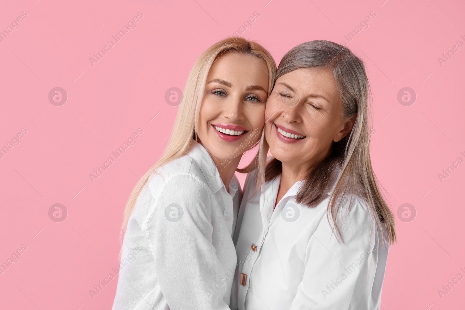 Photo of Family portrait of young woman and her mother on pink background