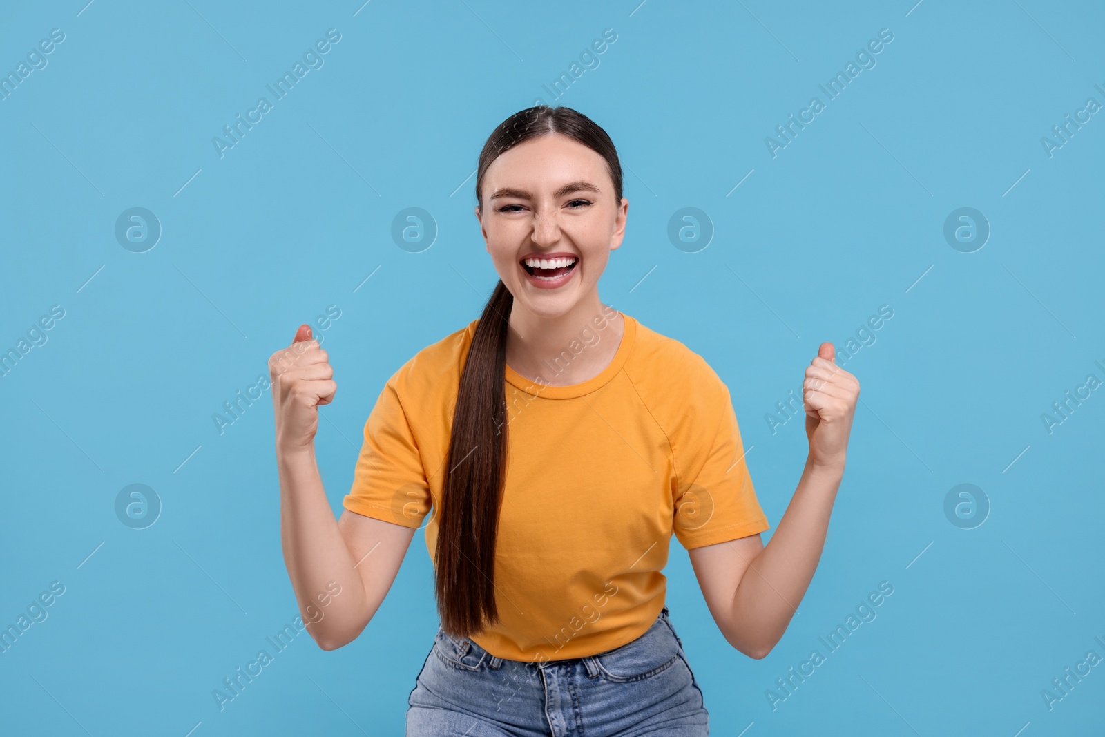 Photo of Happy sports fan celebrating on light blue background