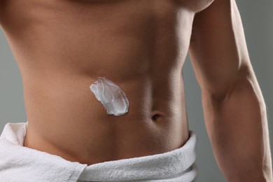 Photo of Man with moisturizing cream on his body against grey background, closeup