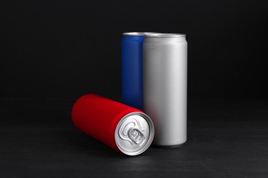 Photo of Energy drinks in colorful cans on black wooden table