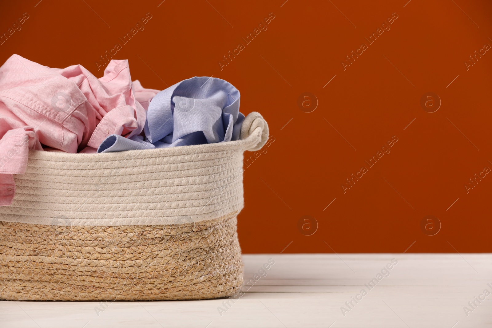 Photo of Laundry basket with clothes near brown wall. Space for text
