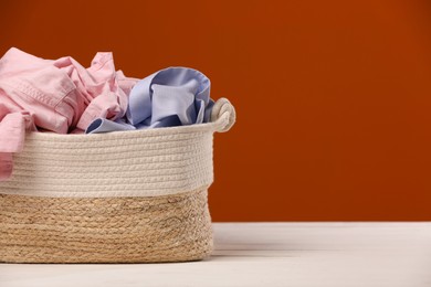 Photo of Laundry basket with clothes near brown wall. Space for text