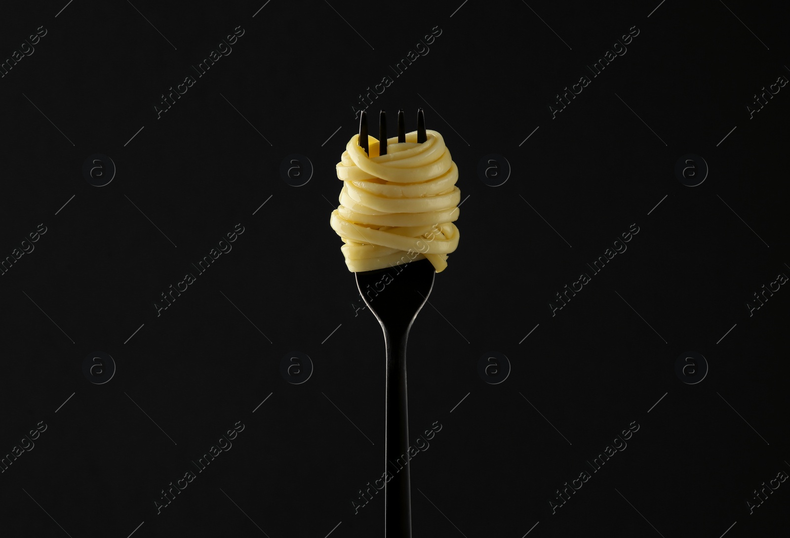 Photo of Fork with tasty pasta on black background